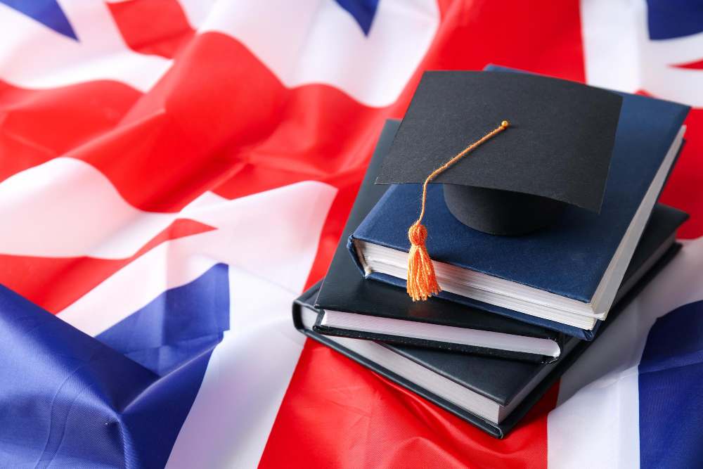 Graduation cap and books on top of a UK flag